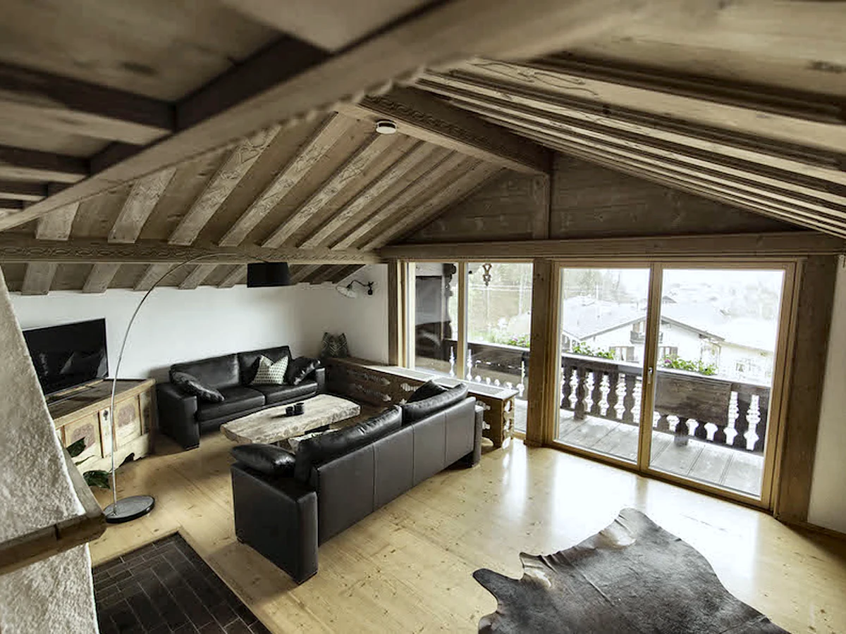 Wohnzimmer der Ferienwohnung mit sichtbarem Dachstuhl und Balkon
